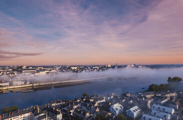 A stunning aerial perspective captures the enchanting Loire Valley at dawn, where mist envelops the serene riverbanks