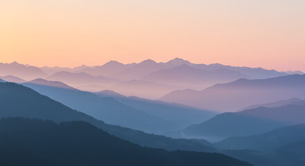 Obraz premium Mountain Layers at Sunset: A serene panoramic view of layered mountains enveloped in a soft, ethereal haze under a pastel sunset sky, evoking a sense of tranquility and vastness.