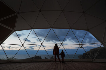 A woman with a child looks at a beautiful sunset. A vacation with incredible views of the sea and mountains. High quality photo