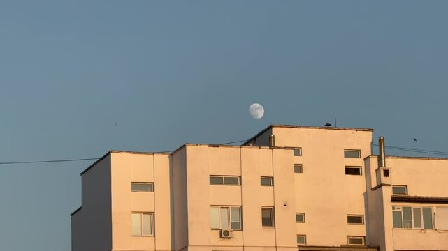 Moon Over Residential Building at Sunset with birds flying