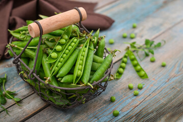Pods of green peas in a metal basket