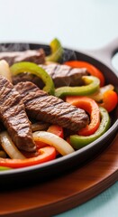 Hot and Delicious Steak Fajitas in a Sizzling Cast Iron Skillet with Bell Peppers and Onions, Perfect for a Mexican Fiesta Dinner served on a wooden plate .