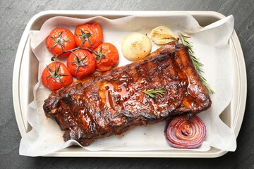 Delicious spare ribs, rosemary, baked onion and sun dried tomatoes on grey textured table, top view