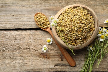 Dry and fresh chamomile flowers on wooden table, flat lay. Space for text