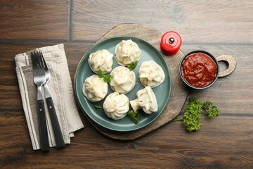 Delicious khinkali served with cilantro on wooden table, flat lay