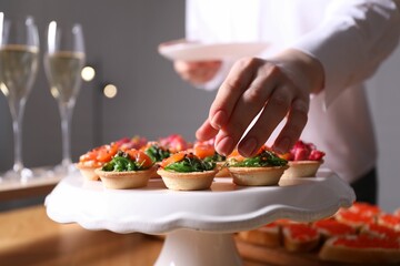 Buffet menu. Woman taking tasty tartlet from table, closeup