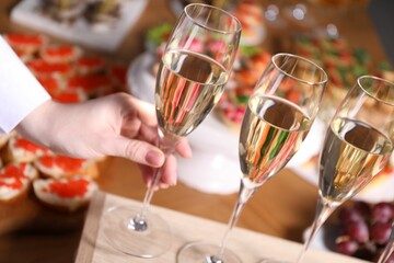 Buffet menu. Woman taking glass of sparkling wine from table, closeup