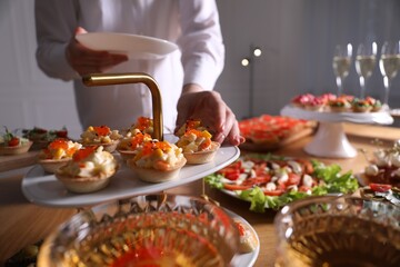 Buffet menu. Woman taking tasty tartlet from table, closeup