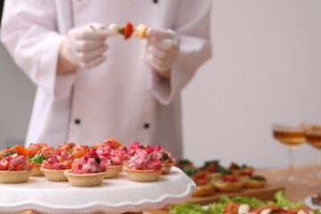 Chef arranging appetizers on buffet table, selective focus