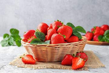 Delicious ripe strawberries and green leaves on grey table, closeup
