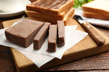 Sandwiches with chocolate butter and knife on wooden table, closeup