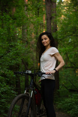 Beauty fun smiling sport woman biking on bicycle on path among green trees in a forest background....