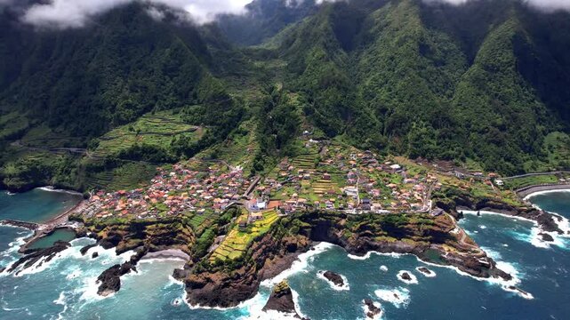 Cinematic aerial view of Seixal natural volcanic lava pools and dragon tail rock formation with ocean waterfall on Madeira island North coast Portugal 4K