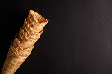 Several waffle cones are stacked upright, showcasing their texture and shape against a dark...