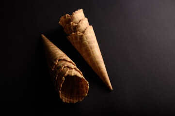 Waffle cones and sugar cones are arranged in a visually appealing manner against a dark backdrop,...