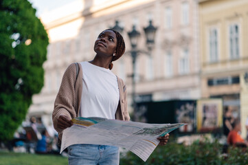Tourist exploring a new city using a map and looking up at buildings
