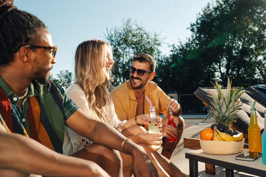 Friends enjoying drinks by the pool on sunny summer day - Powered by Adobe