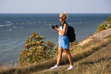 A female tourist and photographer with a backpack explores the picturesque coast of Estonia,...
