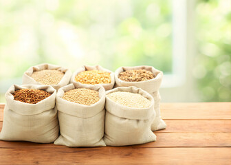 Variety of whole grains in linen sacks arranged on farmhouse table