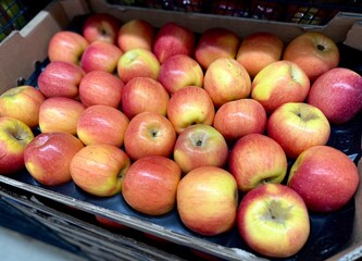 Fresh apples are neatly packed in a box for sale at the store. Vibrant colors and natural texture...