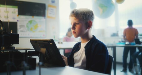 Elementary School Boy Writing Code for Advanced Automated 3D Printer on Tablet Computer During Programming Lesson. Smart Young Boy Studying Technology in Modern Classroom. Interactive STEM Education.