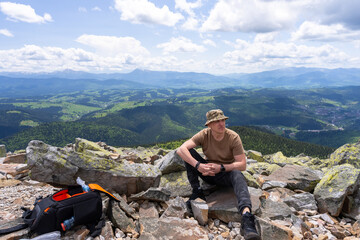 A tourist is resting on the top of a mountain.