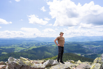 A hiker rests standing on the top of a mountain.