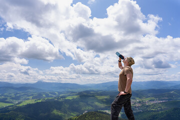 Water is being drank by a tourist against the backdrop of a mountainous landscape.
