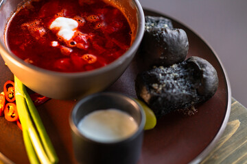 Sour cream is added to a bowl of red borscht.
