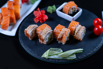 Various sushi rolls on a black plate.