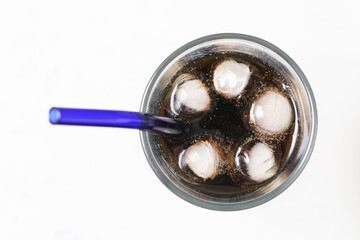 Glass of cola with ice cubes. Purple straw in cold soda drink. Bright white background. Refreshing...