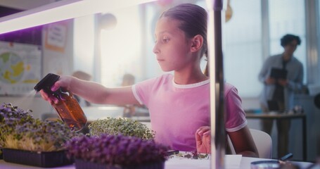 Elementary School Girl Sitting at Table, Growing Experimental Microgreens, Using Tweezer and...