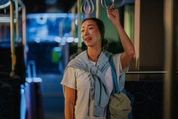 Tourist holding handrail on moving bus at night