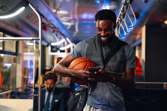 Smiling basketball player using smartphone on bus after training - Powered by Adobe