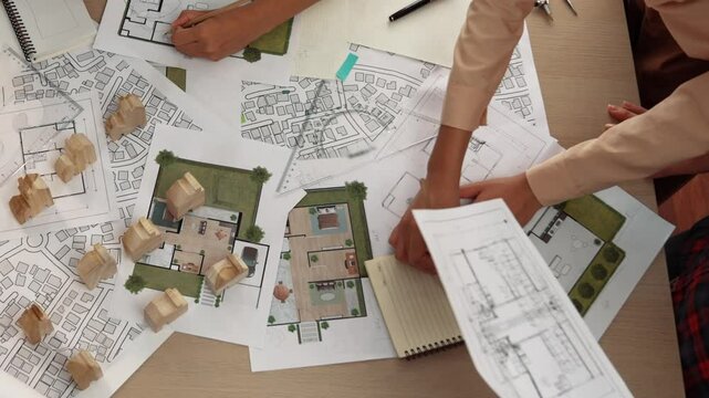 Architect and safety engineer discussion about building construction use blueprint on table with architectural document, measurement tool and wooden block scatter around at modern office. Delineation.