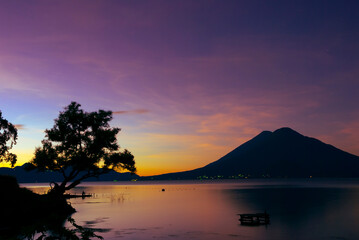 Starry night over Lake Atitl&aacute;n, Guatemala. Long exposure captures stars, volcanoes and colorful village lights reflecting on calm water, evoking peace, wonder, and adventure under the vast sky.