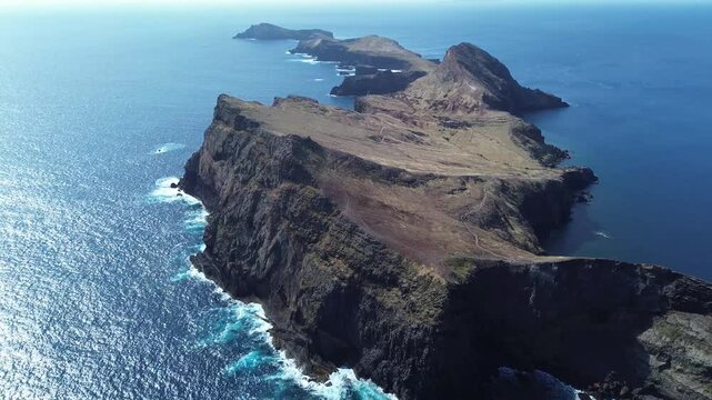 Breathtaking aerial view of vibrant volcanic cliffs meeting the Atlantic Ocean at the edge of Madeira&rsquo;s wild peninsula &mdash; Praia do Sardinha and Vereda da Ponta de S&atilde;o Louren&ccedil;o captured in 4K cinematic 