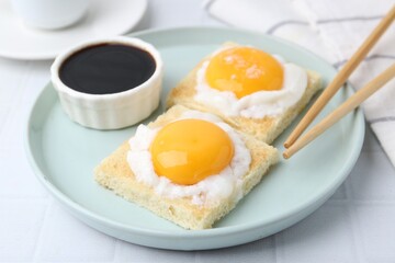 Tasty kaya toasts with half-boiled eggs served on white tiled table, closeup. Traditional asian breakfast