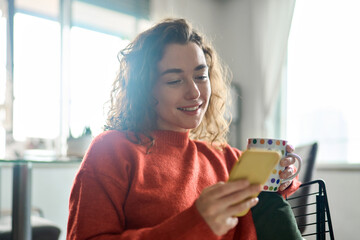 Smiling pretty lady holding smartphone enjoying mobile shopping, checking news on smartphone in...