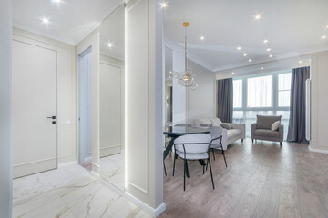 Stylish interior of the living room in the studio apartment. White room decor, parquet floor, elegant furniture.