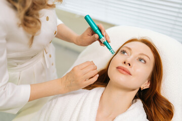 Top view portrait of redhead female receiving rejuvenation treatment in cosmetology clinic....