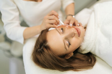 Top view of unrecognizable beautician applying markup grid with white pencil, preparing facial skin...