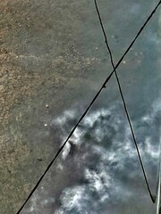 abstract background of the reflection of the clouds in a puddle and also the X-shaped electric wires