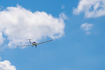 A red and white painted glider gliding in the blue sky