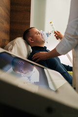 Vertical shot of unrecognizable female doctor assisting to male patient undergoing respiratory training with oxygen mask, providing essential care and monitoring progress in modern medical clinic.