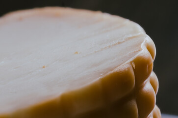 Very detailed macro photo of a sliced piece of textured cheese on a black background