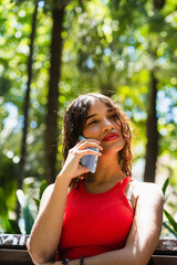 Fototapeta premium Young woman talking on mobile phone in park
