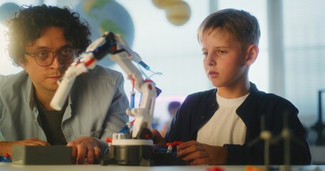 Talented Boy Studying Robotic Arm Model with Teacher. Young School Student During Science and...