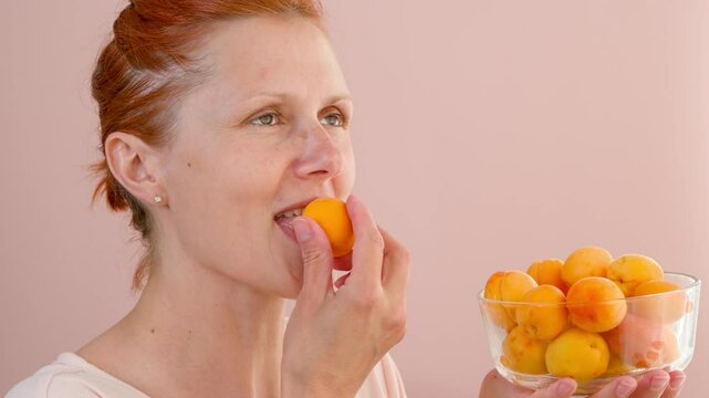 Woman eats ripe apricots. Fruit snack.

