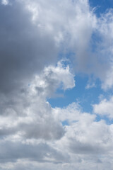 Portrait orientation view of scattered white clouds in blue sky on a clear January midday